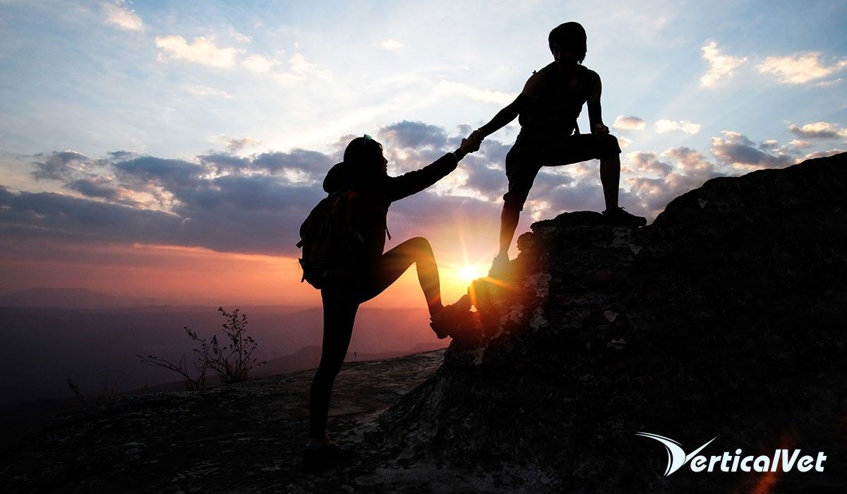man-helping-woman-up-mountain-hiking
